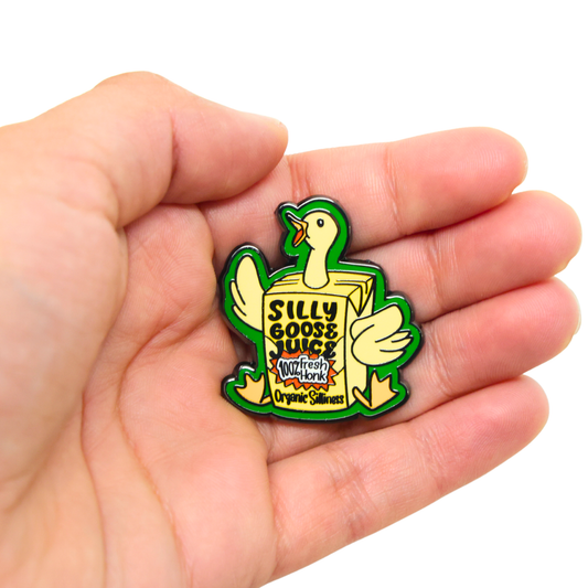 Pin with a duck design on a box labeled 'Silly Goose Juice' held in a hand.