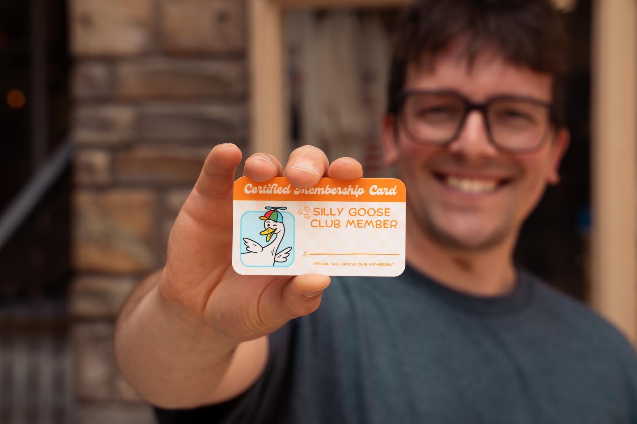 Nate holding a 'Silly Goose Club' membership card outdoors