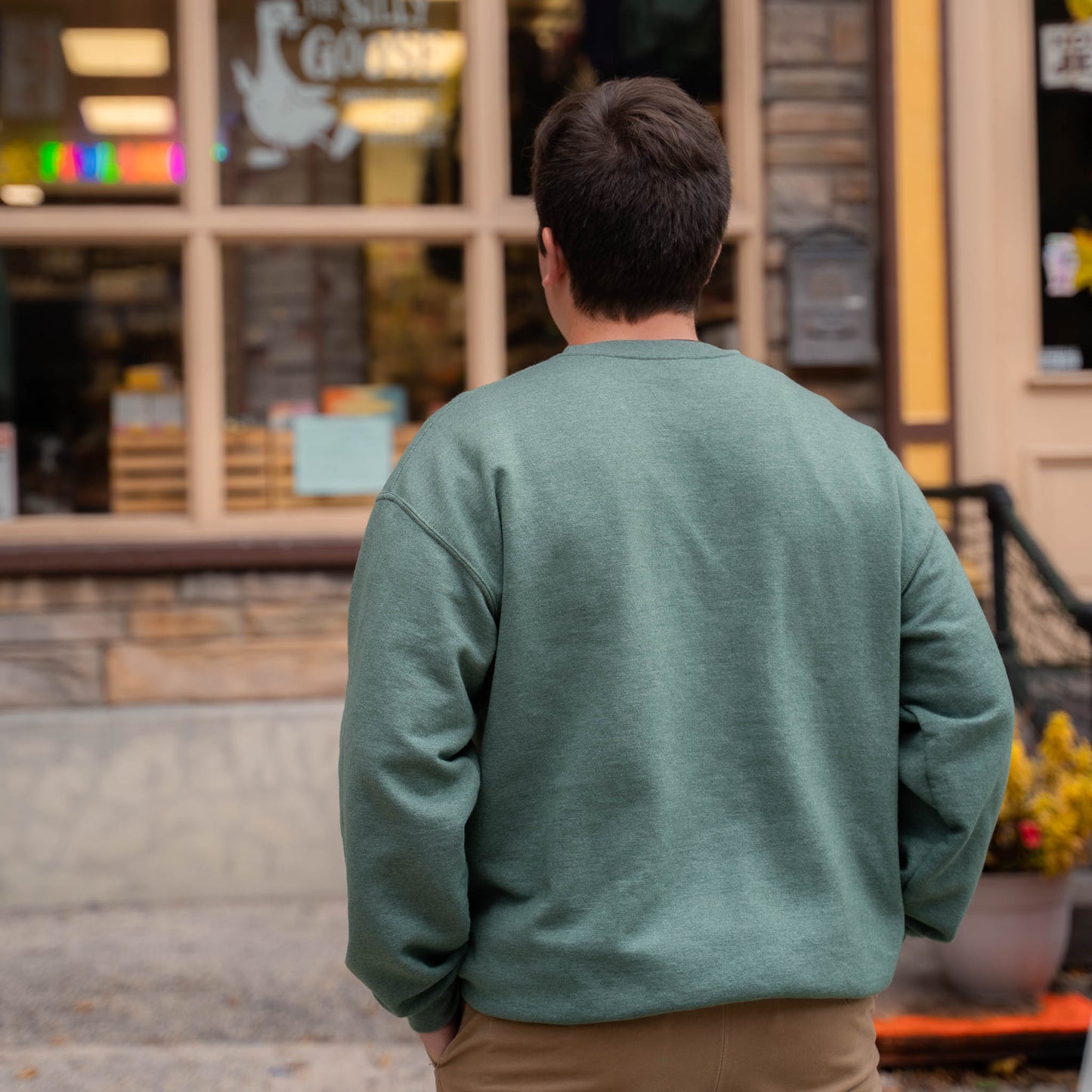 Nate in front of The Silly Goose in Jim Thorpe wearing a green Silly Goose University Crew Neck
