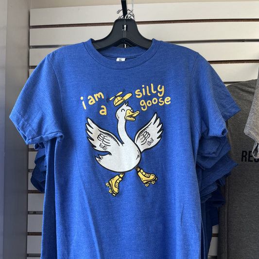 Blue t-shirt with a cartoon goose graphic and text on a hanger against a striped wall.