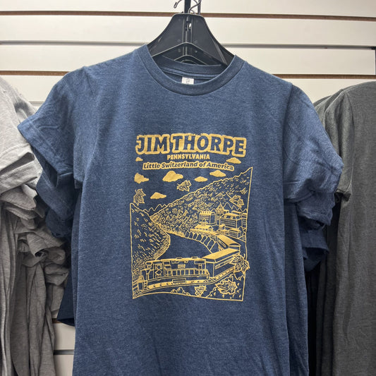Blue t-shirt with yellow graphic and text on a hanger against a wall of other shirts.