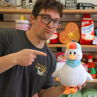 Nate from The Silly Goose holding a plush toy duck with a shelf of decorative items in the background
