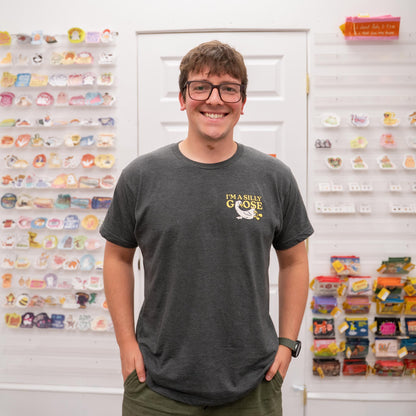 Nate wearing a dark gray t-shirt with a graphic design in front of a display wall.