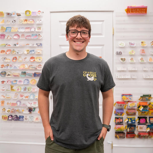 Nate wearing a dark gray t-shirt with a graphic design in front of a display wall.