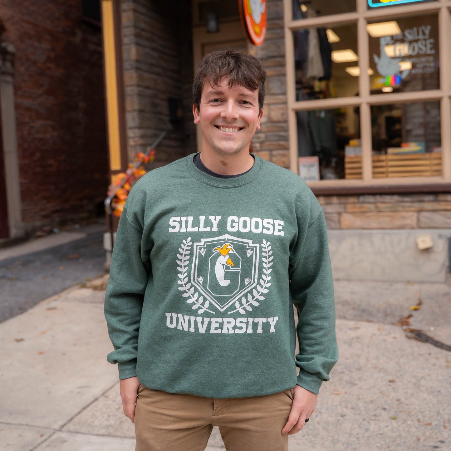 Nate in front of The Silly Goose in Jim Thorpe wearing a green Silly Goose University Crew Neck